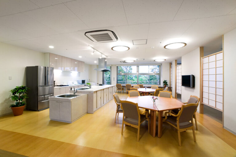 広々とした食堂兼キッチン。木製テーブルと椅子、大きな窓から自然光が入る明るい空間